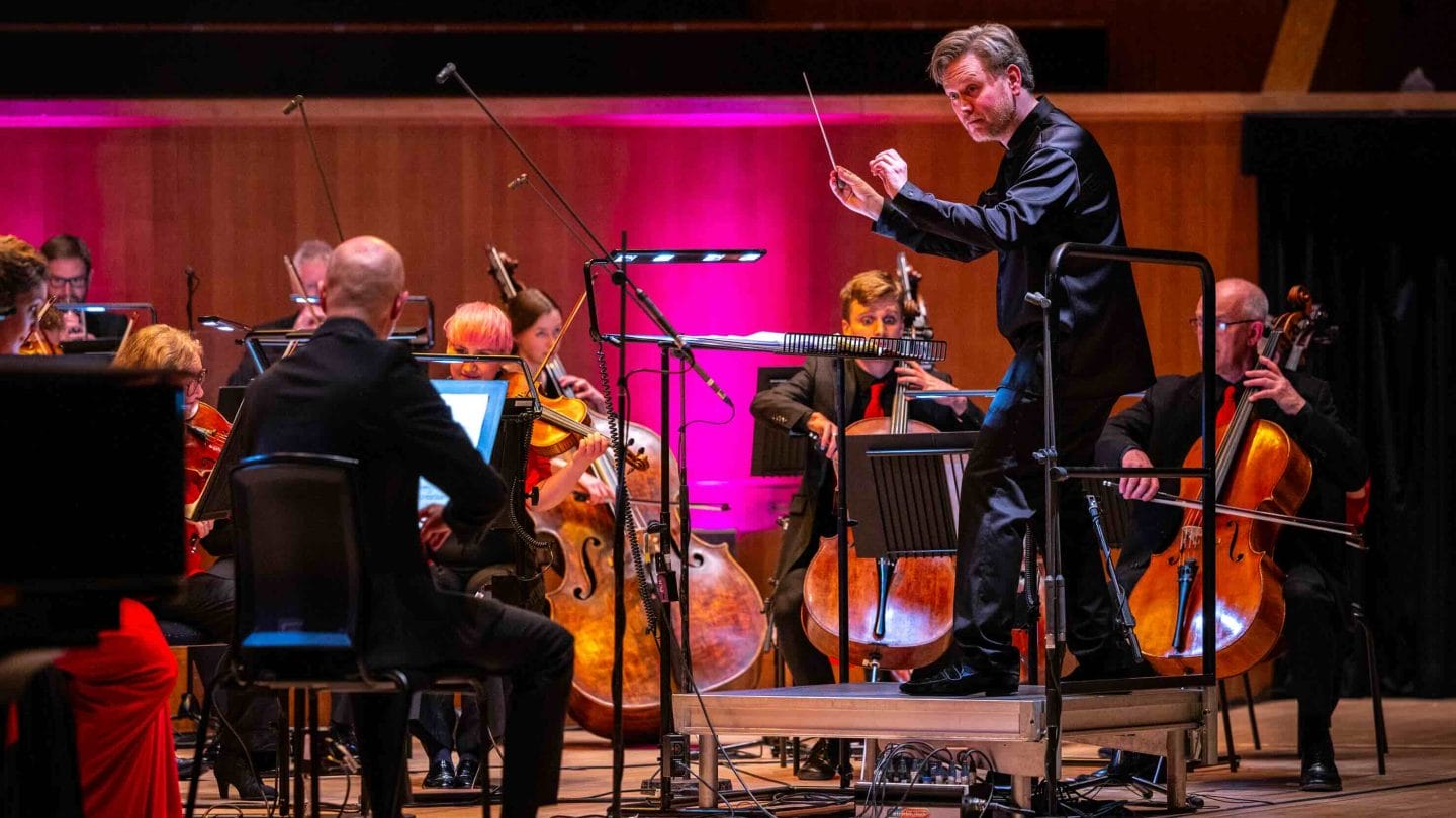 Action shot of conductor in a satin suit.
