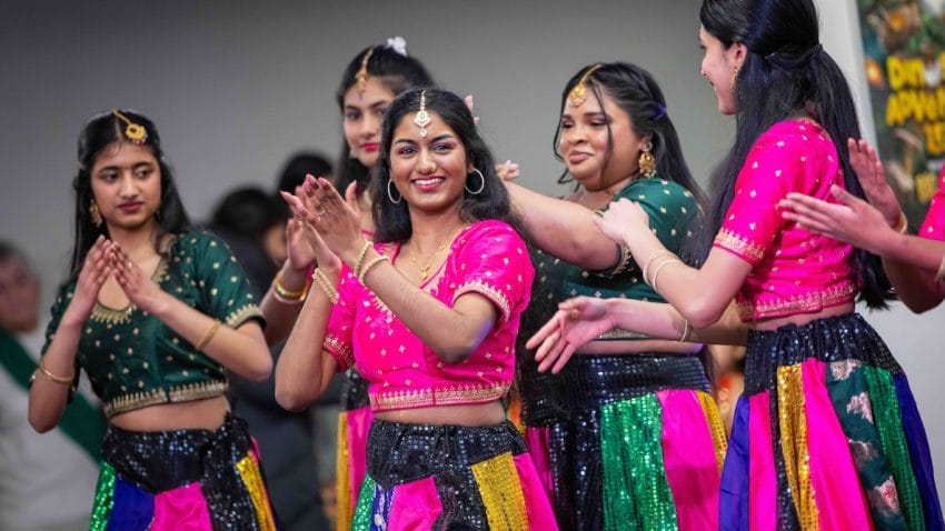 A woman from a South Asian dance group smiles at the camera.