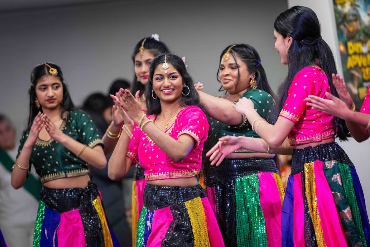 A woman from a South Asian dance group smiles at the camera.
