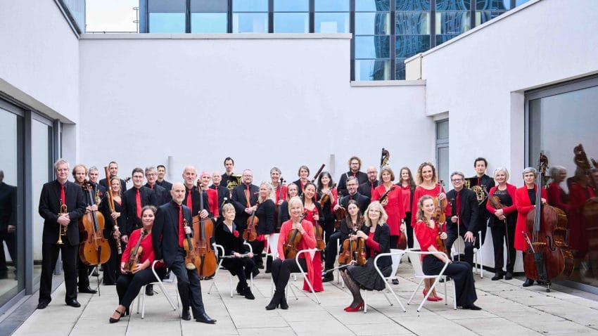 Musicians pose with instruments in outside patio space.