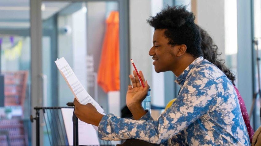 Man reads from sheet music and holds pencil.