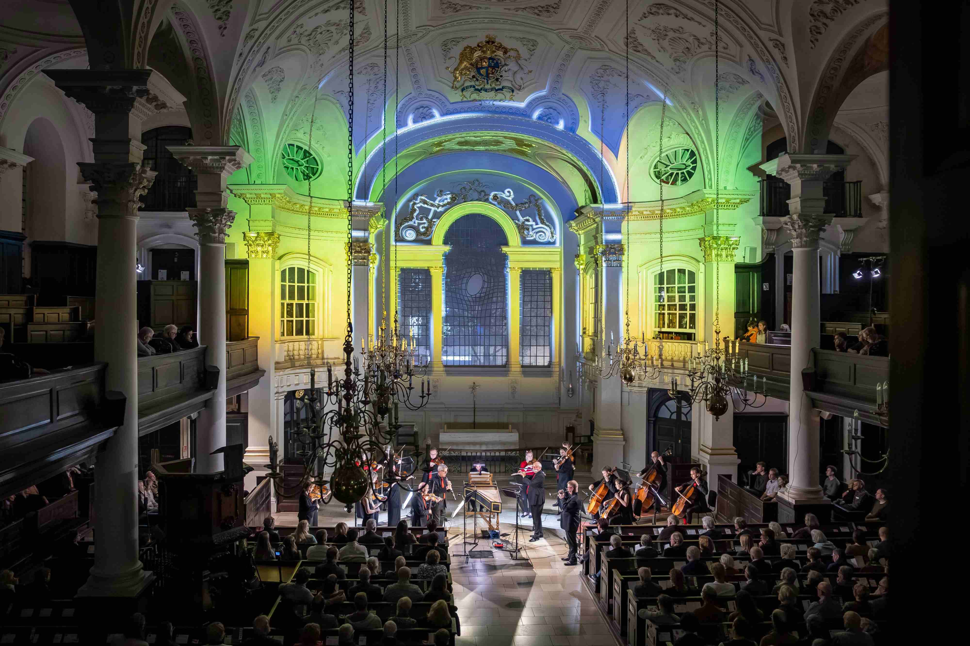 Beautiful patterns are projected on the back wall of a church, over the heads of musicians.