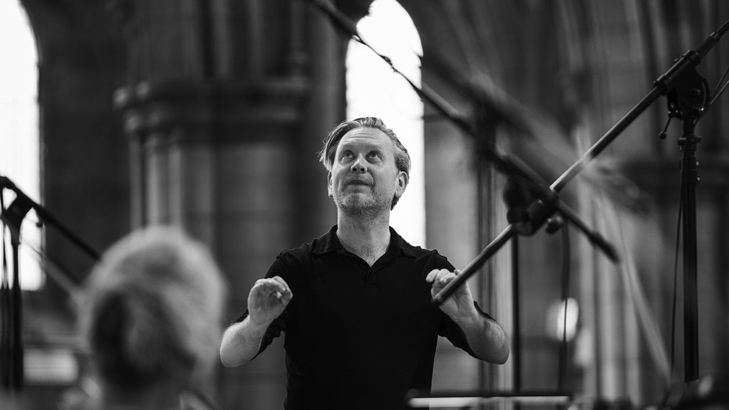 A black and white image of a man looking up while conducting.