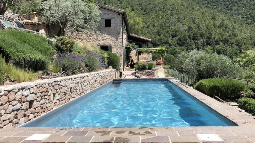 A beautiful, blue pool is drenched in sunlight amongst a backdrop of rolling Italian hills