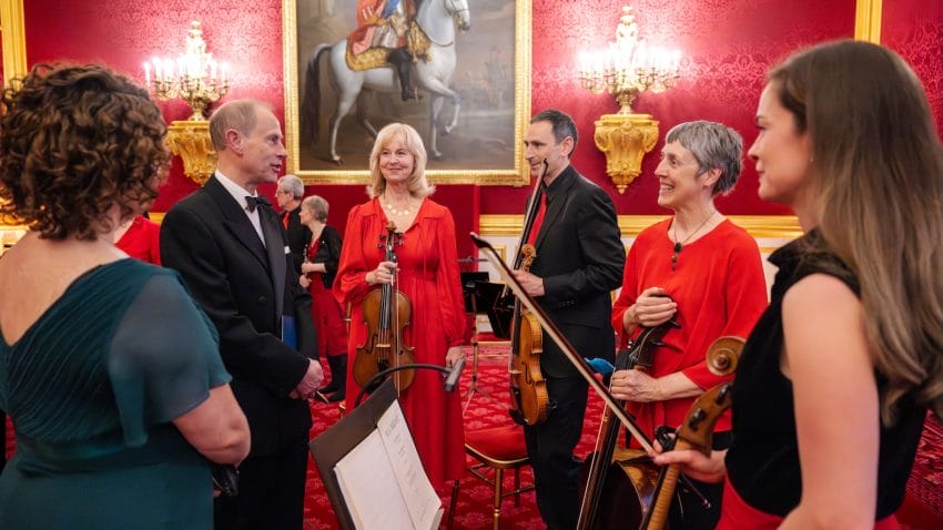 His Royal Highness the Duke of Edinburgh stands amongst orchestra members
